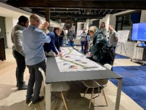 Project team member reviews map of proposed project plans with open house attendees.